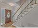 Bright foyer with hardwood floors, staircase with white railings, and a decorative front door at 8704 Paddle Wheel Dr, Raleigh, NC 27615