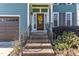 Inviting brick front porch with a wooden door, yellow wreath, and manicured landscaping at 8704 Paddle Wheel Dr, Raleigh, NC 27615