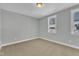 A bright bedroom has light walls, carpet flooring and natural light from two windows with white trim at 9152 Dupree Meadow Dr # 12, Angier, NC 27501