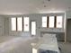 Unfinished living room with large windows, door to backyard, and grey kitchen cabinets at 9152 Dupree Meadow Dr # 12, Angier, NC 27501