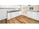 Well-lit kitchen with white cabinets, a stainless steel sink, and wood floors at 1402 Valley Rd, Garner, NC 27529
