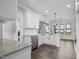 Open kitchen with white cabinets, granite countertops, stainless steel appliances, and dark wood floors at 151 S Harper Faith Way, Benson, NC 27504