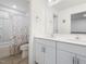 Clean bathroom with double sinks, white cabinetry, tile floors, and a bathtub with floral shower curtain at 182 Mill Bend Dr, Fuquay Varina, NC 27526