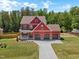 The aerial view shows a large, red home with a well-manicured lawn, long driveway, and attached three-car garage at 182 Prince Place Dr, Fuquay Varina, NC 27526