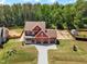 Aerial view of a spacious, red two-story home showcasing its manicured lawn, driveway and surrounding trees at 182 Prince Place Dr, Fuquay Varina, NC 27526