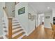 Inviting hallway with hardwood floors, white trim, natural light, and a staircase leading to upper levels at 182 Prince Place Dr, Fuquay Varina, NC 27526