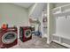 Spacious laundry room with modern machines, tile flooring, built-in shelving, and a convenient coat rack at 182 Prince Place Dr, Fuquay Varina, NC 27526