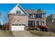 Inviting exterior showcasing a brick facade, two-car garage, manicured lawn, and covered front porch at 1950 Firenza Dr, Apex, NC 27502