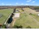 Wide aerial view of a large estate with a white farmhouse, equestrian arena, and sprawling green land at 2142 Henderson Tanyard Rd, Pittsboro, NC 27312