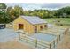 Newly built wood barn with a metal roof, surrounded by fencing and lush green trees at 2142 Henderson Tanyard Rd, Pittsboro, NC 27312