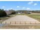 Expansive equestrian arena with wood perimeter fencing and a beautiful white farmhouse in the background on a sunny day at 2142 Henderson Tanyard Rd, Pittsboro, NC 27312