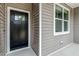 Modern black front door with glass window panel, framed with light gray siding and white trim at 220 Shawnee Dr, Louisburg, NC 27549