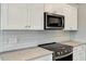 Kitchen features stainless steel appliances, white subway tile backsplash and white cabinetry at 220 Shawnee Dr, Louisburg, NC 27549