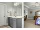 Bathroom vanity with a large mirror, light fixtures, and neutral paint, leading into the primary bedroom at 236 Star Valley Dr, Angier, NC 27501