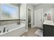 Bright bathroom showcasing a soaking tub with decorative tile, a window, and wood-look tile flooring at 236 Star Valley Dr, Angier, NC 27501