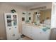 The bathroom features dual sinks, white cabinets, a large mirror and window with plantation shutters at 3516 Apache Dr, Raleigh, NC 27609