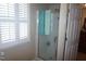 Bathroom with enclosed shower, glass door, tile floor, and large window with plantation shutters at 3516 Apache Dr, Raleigh, NC 27609