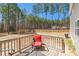 Outdoor wooden deck with a red chair and a view of the fenced backyard with tall trees at 40 Poplar Bark Dr, Youngsville, NC 27596
