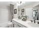 Bathroom with double vanity sinks, framed art, patterned curtains, and a combination tub and shower at 408 Rowe Way, Knightdale, NC 27545