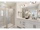 Bright bathroom featuring double sinks, white cabinetry, tiled shower with glass door and natural light at 408 Rowe Way, Knightdale, NC 27545
