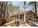 Single story brick home featuring a long covered porch surrounded by mature trees at 4105 Lassiter Rd, Wake Forest, NC 27587