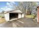 View of detached garage with an open bay, a concrete driveway and a partial view of the backyard at 413 S Maple St, Graham, NC 27253