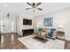 Living room with hardwood floors, neutral walls, a ceiling fan, television, and front door at 50 Yelverton Ct, Holly Springs, NC 27540
