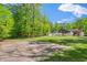 Spacious backyard with mature trees, a basketball court, and the rear exterior view of the home at 5313 Edington Ln, Raleigh, NC 27604