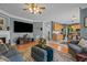 Open living room with a ceiling fan, large TV, hardwood floors and access to the kitchen and dining area at 5405 Seaspray Ln, Raleigh, NC 27610