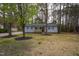 Home features wood front porch, gray siding, black shutters, and mature trees at 602 N Mineral Springs Rd, Durham, NC 27703
