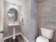 Stylish powder room with patterned wallpaper, pedestal sink, round mirror, and modern fixtures at 1005 Red Roses Ave, Durham, NC 27703