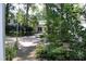 Charming home exterior showcasing lush landscaping, a brick pathway, and mature trees at 1309 Langdon Pl, Pittsboro, NC 27312