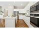Bright and open kitchen featuring stainless steel appliances, white cabinetry, and hardwood floors at 1309 Langdon Pl, Pittsboro, NC 27312