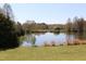 Scenic view of a tranquil pond surrounded by trees and a well-manicured grassy area at 1309 Langdon Pl, Pittsboro, NC 27312
