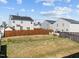 View of backyard showing grass, a wooden fence, and neighboring houses at 1445 Lombar St, Raleigh, NC 27610