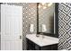 Bathroom features black and white patterned wallpaper, a white vanity, and modern lighting at 1925 Banbury Rd, Raleigh, NC 27608