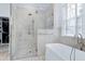 Bright bathroom features a glass shower, soaking tub, and marble tile at 1925 Banbury Rd, Raleigh, NC 27608