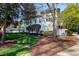 Rear exterior with a lush green lawn, a mature tree, and a white brick facade at 1925 Banbury Rd, Raleigh, NC 27608
