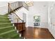 Bright foyer with hardwood floors, staircase with green runner, and view into the dining room at 1925 Banbury Rd, Raleigh, NC 27608