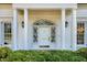 Elegant front door framed by white columns and sidelights, enhanced by manicured landscaping and exterior lighting at 1925 Banbury Rd, Raleigh, NC 27608