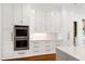 Bright kitchen featuring custom white cabinetry, gold hardware, and modern built-in stainless steel appliances at 1925 Banbury Rd, Raleigh, NC 27608