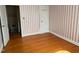 Bedroom featuring wood floors, striped wallpaper, and a closet with a coat rack at 2121 Allensville Rd, Roxboro, NC 27574
