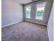 Bedroom with two windows looking out onto green trees and carpeted floor at 217 Duncan Creek Rd # 124, Lillington, NC 27546