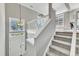 Bright stairway featuring gray walls, white railings, carpeted stairs, and a front door view at 3001 Imperial Oaks Dr, Raleigh, NC 27614