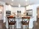 Bright kitchen with white cabinets, stainless appliances, a tile backsplash, and an island with bar stools at 3009 Kildaire Dairy Way, Apex, NC 27539