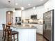 Modern kitchen with white cabinets, a stainless steel refrigerator, and a stylish island with seating at 3009 Kildaire Dairy Way, Apex, NC 27539