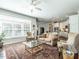 Cozy living room with large windows, a ceiling fan, and an adjacent modern kitchen at 3009 Kildaire Dairy Way, Apex, NC 27539