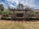 Community entrance sign featuring stone pillars, wooden pergola, and manicured landscaping at 3009 Kildaire Dairy Way, Apex, NC 27539