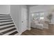Bright living room featuring hardwood floors, large windows, and stairs leading to the upper floor at 3360 Brevet St, New Hill, NC 27562