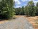 Gravel driveway leads to a cleared homesite surrounded by lush trees and a vibrant blue sky at 3400 River Manor Ct, Franklinton, NC 27525